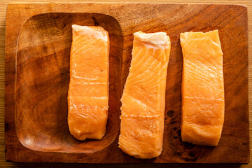 raw salmon fillets on a wooden plate