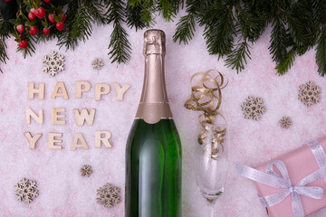 candies, a bottle of champagne, a glass, spruce branches and the inscription: "Happy New Year" on a snow-covered table