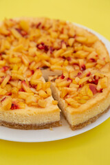 Fresh cheesecake on a plate on yellow background.