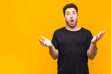 young man feeling extremely shocked and surprised, anxious and panicking, with a stressed and...