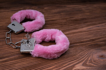 Handcuffs with pink fur on a wooden table. bdsm role play sexy