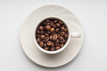 White coffee cup with coffee beans on a saucer, white background