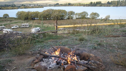 campfire in the forest with a lake in the background