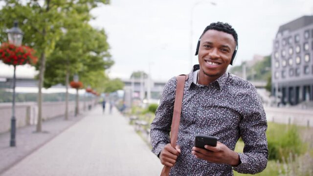 Young black man commuter outdoors in city, walking.