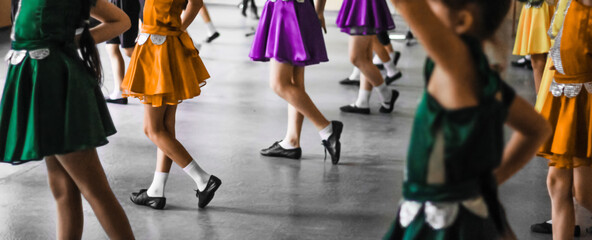 Fototapeta na wymiar Little girls dancing in colorful Christmas party dresses of yellow, purple, and green colors. Defocused web banner with space for text