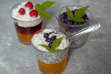 Dessert with chia seeds and berries in glass glasses on a wooden board on a gray background. Superfoods and healthy lifestyle concept.