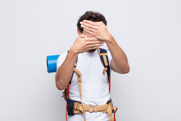young man covering face with both hands saying no to the camera! refusing pictures or forbidding...