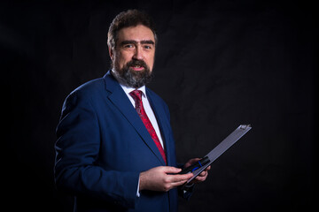 Mature businessman dressed in blue suit with red tie studio portrait.