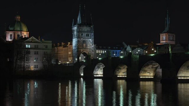 
Timelapse illuminated Charles Bridge from 14 centuries and light from street lighting and stone sculptures on the bridge and light reflections on the surface of the Vltava river at night in  Prague
