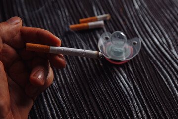 Stop smoking concept. Hand with cigarettes and baby pacifier.