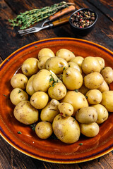 New young boiled potato with butter and chopped dill. Dark Wooden background. Top view