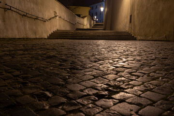 
sidewalk with cobblestones for pedestrians and light from street lights in the center of Prague at night
