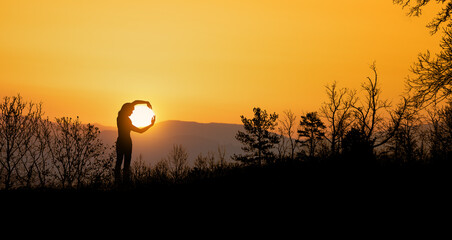 woman catches the setting sun with her arms