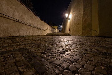 
sidewalk with cobblestones for pedestrians and light from street lights in the center of Prague at night