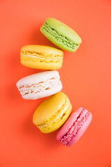 Colorful background. Beautiful bright colorful macaroons on the orange background. Bright background and macaroons.