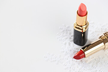 Two red lipsticks and decorative snow on a white background. Isolated. Copy space. Cosmetic concept.