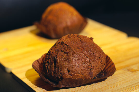 Two delicious handmade chocolate truffles on a wood cutting board