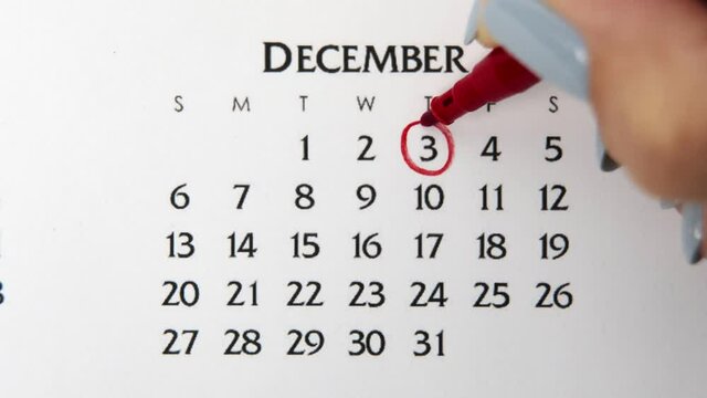 Female hand circle day in calendar date with a red marker. Business Basics Wall Calendar Planner and Organizer. December 3th