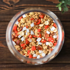 granola in a glass jar on a dark wooden background top view