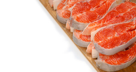 Preparing salmon fillet for cooking, healthy eating concept. Cut in slices fresh raw salmon fillet steak on wooden board, isolated on white panoramic background, top view, copy space