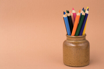 Colored drawing pencils in a variety of colors on a beige background. Close up.