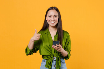 Smiling pretty young brunette asian woman wearing basic green shirt standing using mobile cell...