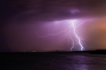Naklejka na ściany i meble lightning striking the horizon during a thunderstorm at night in Formentera, Spain