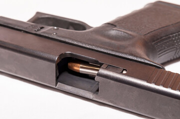 A black 9mm pistol with it's slide open showing a bullet about to be chambered on a white background