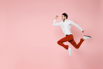 Fototapeta na wymiar Full length side view of shocked screaming young bearded man 20s wearing basic casual white shirt jumping like running looking aside isolated on pastel pink color wall background studio portrait.