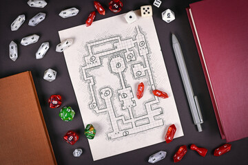 Tabletop role playing flat lay with RPG game dices, hand drawn dungeon map, rule books and pen on...