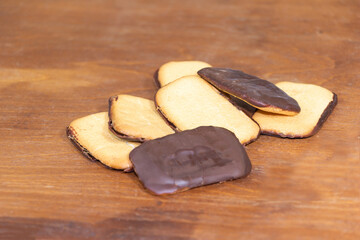 Biscuits with chocolate and with a fine orange fruit filling. Wooden background