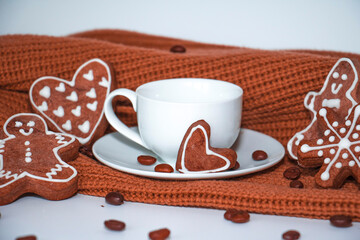 Cup with coffee and gingerbread cookies with a brown scarf on a white background