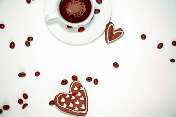 
White cup with coffee, coffee beans and gingerbread cookies in the form of a heart on a white background