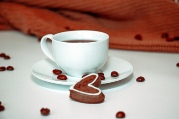 Cup with coffee and gingerbread cookies with a brown scarf on a white background
