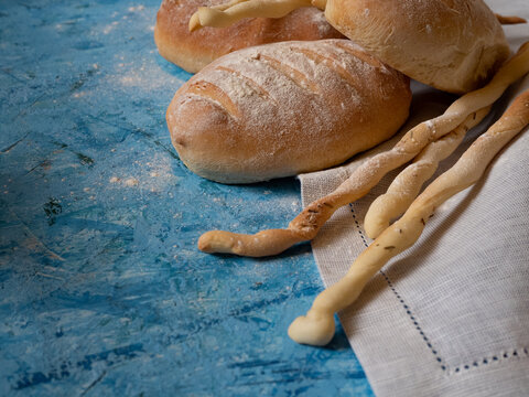 Italian gressini bread sticks and bread. Delicious aromatic pastries on a blue textured background.