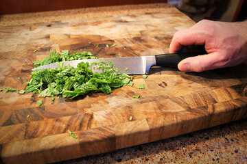 Closeup of a hand holding a knife cutting green mint