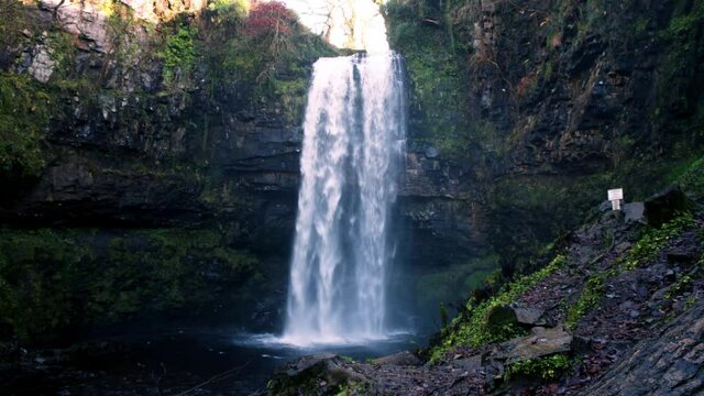 Beautiful view of waterfall, known as henrhyd falls in south wales uk. large amount of water flowning down during the winter season in wales.
