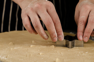 manos cortando galletas de navidad en forma de estrella 