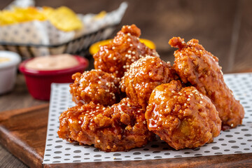 Baked chicken wings with sesame and sauce on wooden background