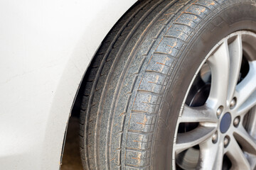 Close up of dirty car wheel with rubber covered rubber tire.