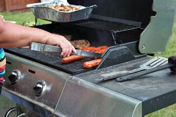 Hotdogs and steak on the grill at a backyard cookout