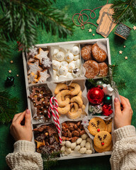 christmas cookies box on green background with girl hands