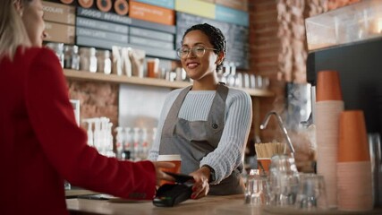 Joyful Multiethnic Diverse Woman Gives a Payment Terminal to Customer Using NFC Technology on Smartphone
