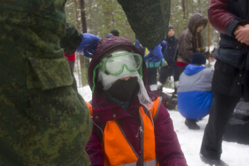 Training in first aid for eye injury. Reportage from a place in the winter forest where the exercises are taking place. Bandaging the victim's head