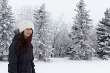 Young girl enjoys a winter scene, fog, frost and snow covered evergreen trees