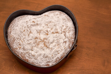 Homemade heart shaped cake, freshly baked and dusted with powdered sugar