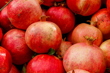 Fototapeta na wymiar Heap of fresh pomegranates for sale in market. Background of pomegranate fruits