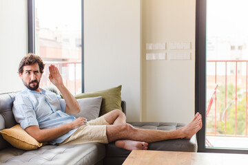 young man looking serious and curious, listening, trying to hear a secret conversation or gossip,...