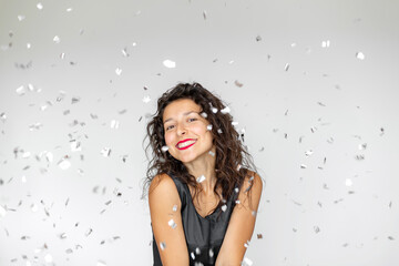 The emotion of success. Happy sexy brunette girl is enjoying celebrating with confetti on a white background