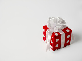 Surprise gift for new year, Christmas, birthday, beloved. Red polka dot box with big bow on white background.